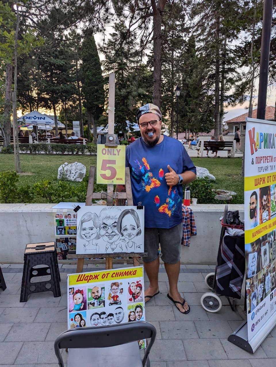 Karikaturist mit seinen Zeichnungen an einem Stand im Park von Obzor