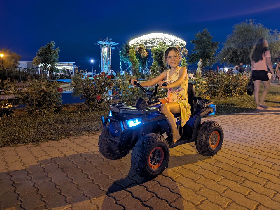 Kind auf einem Elektro-Quad am Abend im beleuchteten Zentrum von Obzor