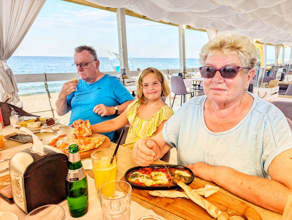 Familie beim Abendessen mit Pizza und Ofengericht im Strandrestaurant Captain Fish mit Meerblick in Obzor