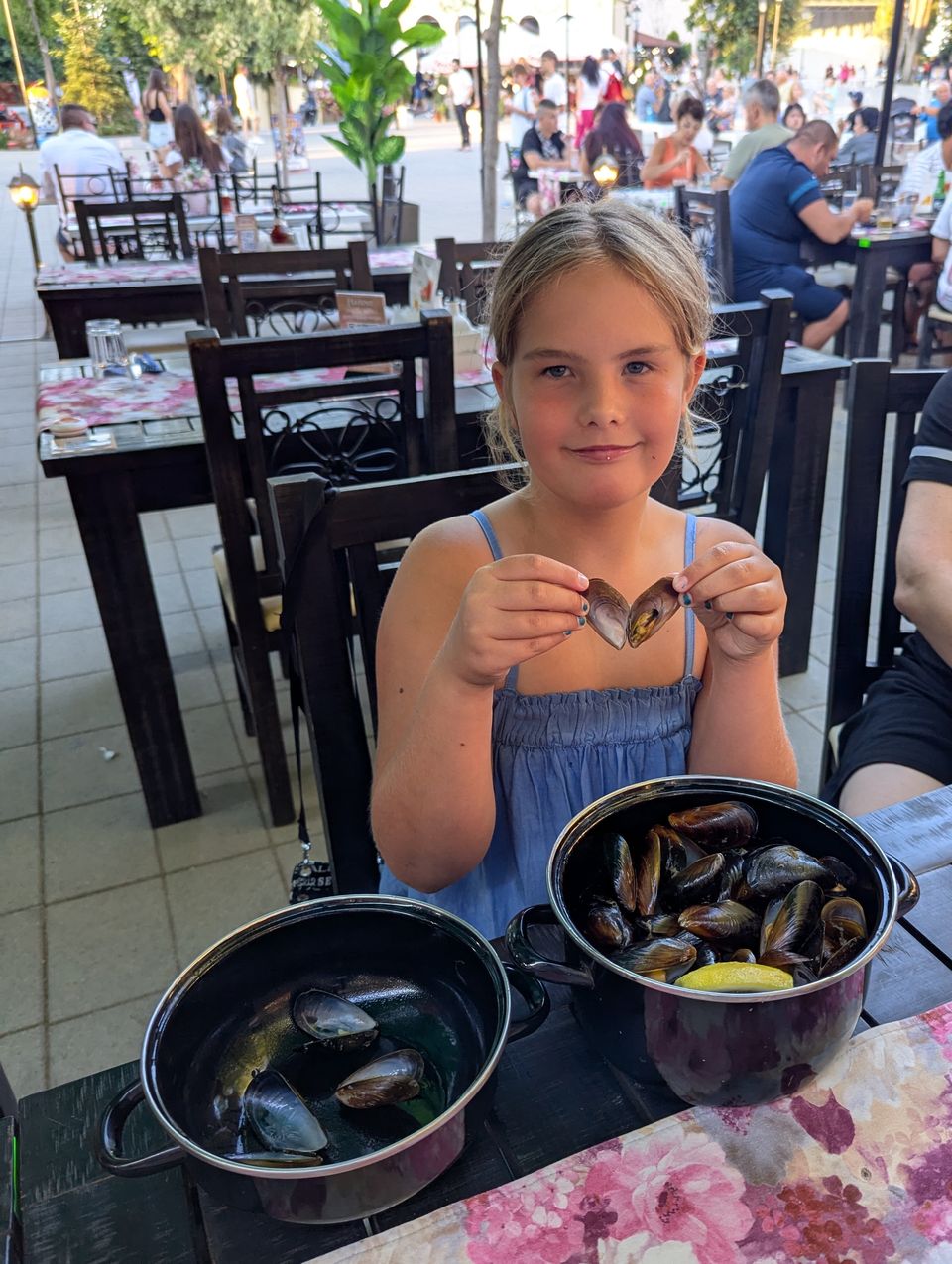 Kind mit zwei Töpfen frischer Muscheln in einem Restaurant an der Promenade von Obzor