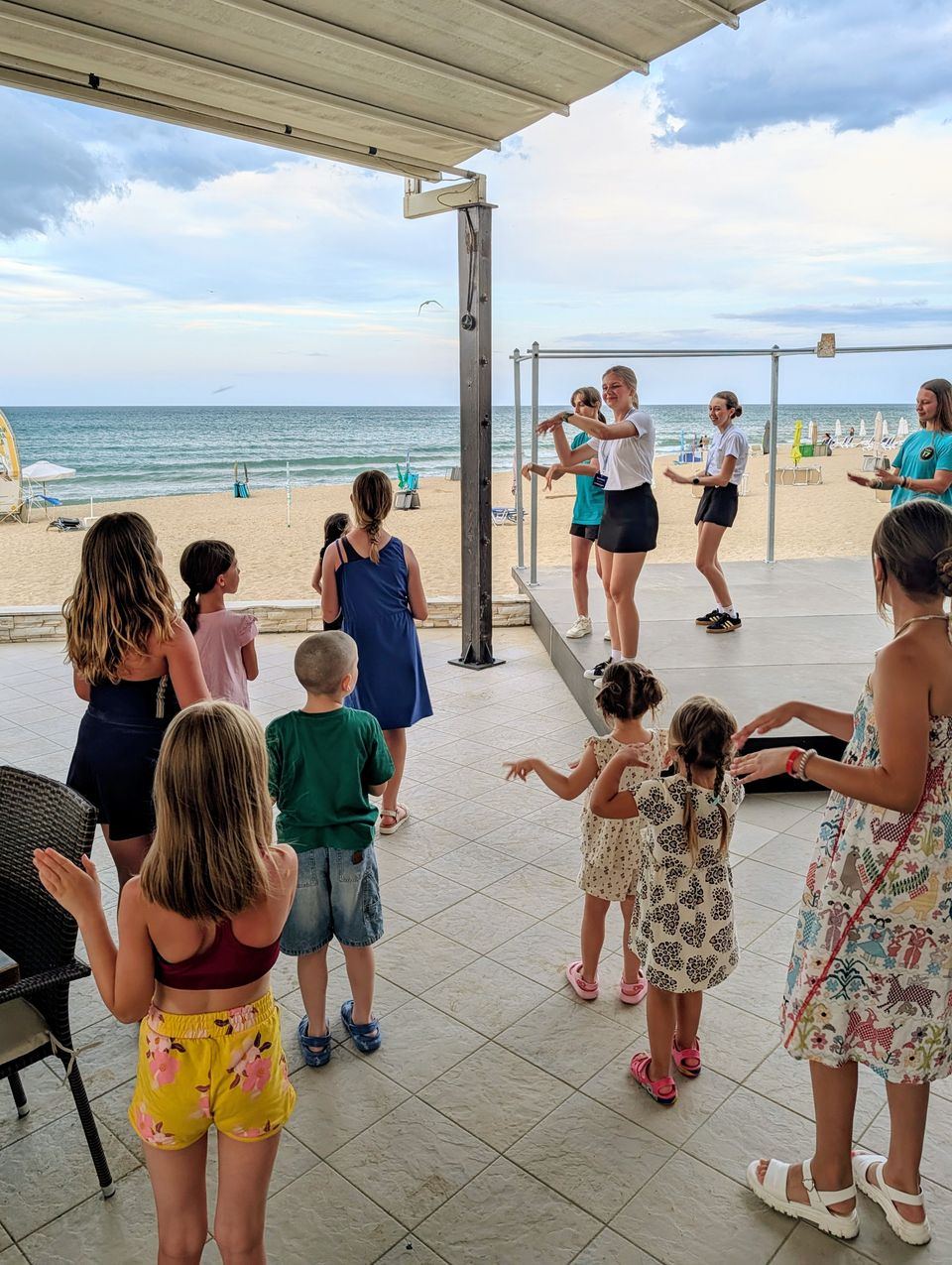 Kinder tanzen bei der Strandanimation im Obzor Beach Resort, dahinter das Meer